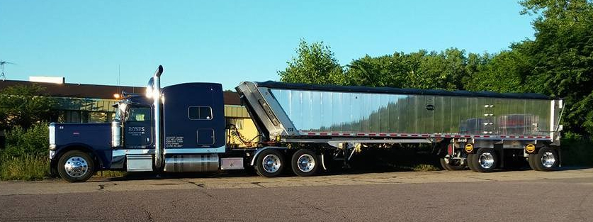 semi truck with navy blue tractor unit and a shiny silver truck bed